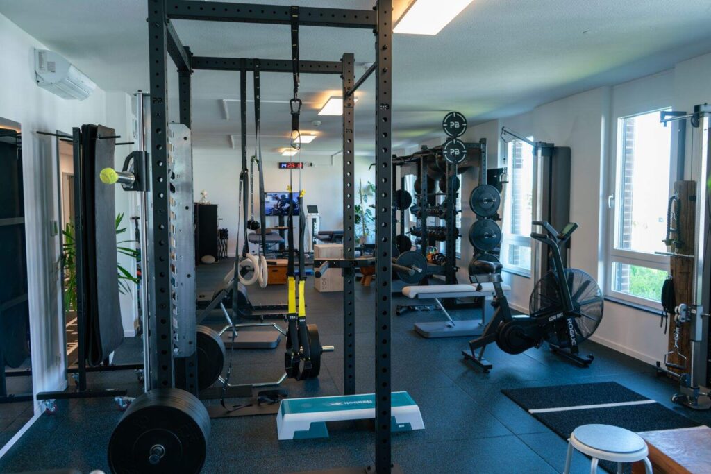 Moderner Trainingsraum in der Physiotherapie Durlach mit Kraftstation, Hanteln und Cardio-Geräten für Reha und Aufbau