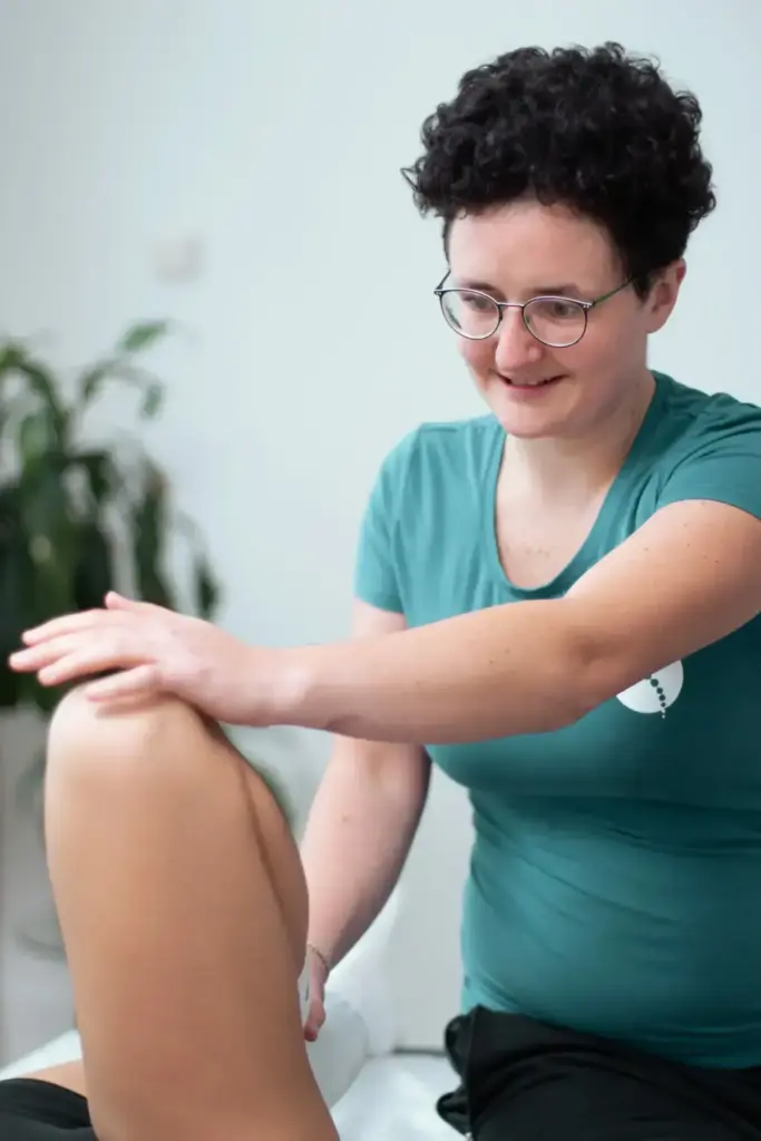 Therapeutin führt klassische Krankengymnastik am Knie durch und mobilisiert das Bein in der Physiotherapie