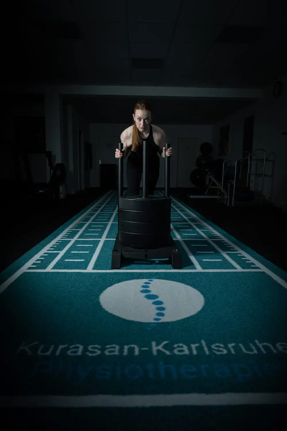 Sportlerin schiebt einen Gewichtsschlitten im Trainingsraum – Athletik- und Reha-Training bei Physiotherapie Karlsruhe