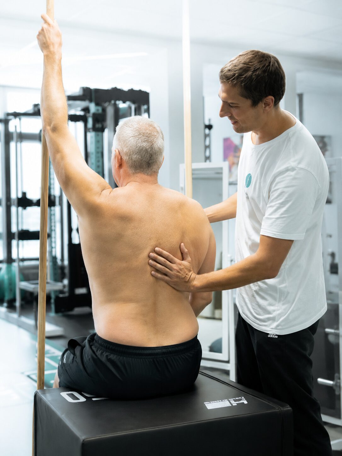 Physiotherapeut begleitet einen Patienten bei einer Übung zur Skoliose Therapie und Haltungskorrektur im Trainingsraum