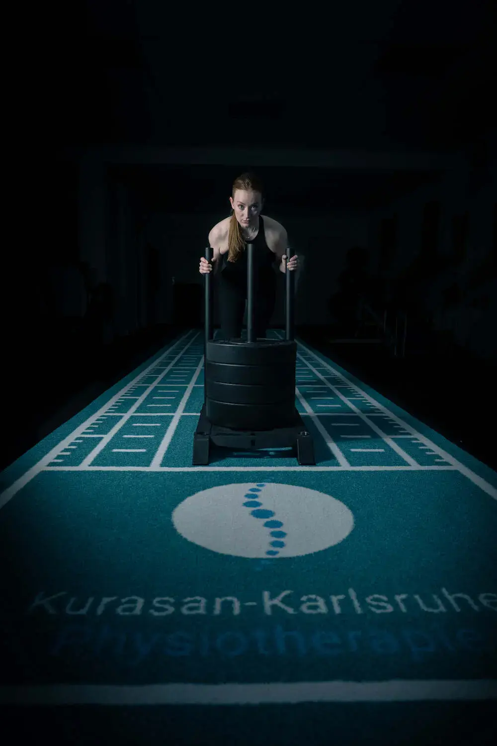 Athletin schiebt einen Gewichtsschlitten im Gym – Sportphysiotherapie Karlsruhe für Training, Prävention und Rehabilitation
